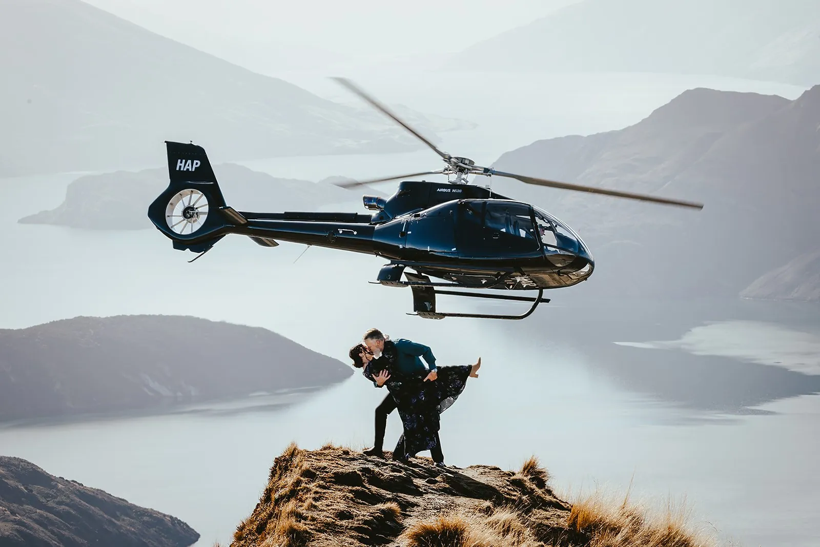 Helicopter flying above a couple eloping on a mountain ridge in Queenstown, New Zealand